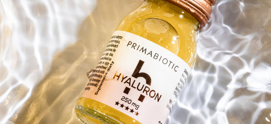 Boccetta di vetro con tappo color rame contenente integratore liquido Primabiotic Hyaluron – acido ialuronico da bere, immersa in acqua con riflessi luminosi.