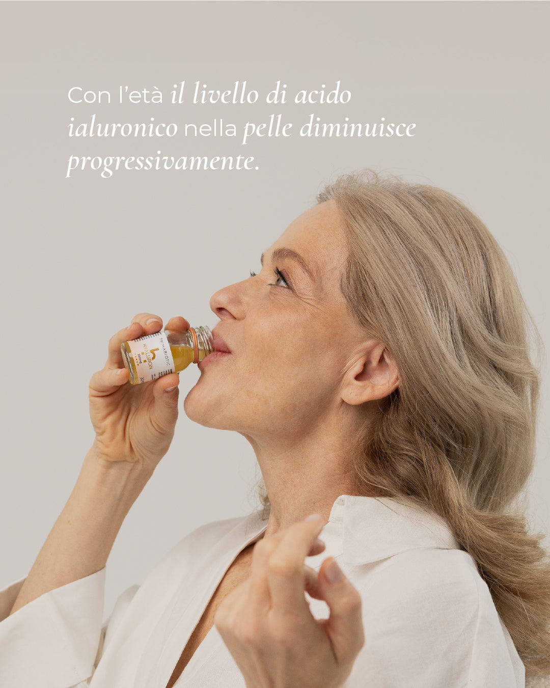 donna matura beve un flaconcino di Primabiotic Hyaluron con scritta Con l’età il livello di acido ialuronico nella pelle diminuisce progressivamente