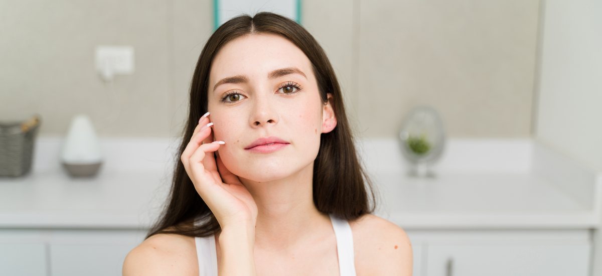 młoda kobieta z gładką i promienną skórą, dotykająca twarzy po zastosowaniu suplementu Primabiotic Collagen