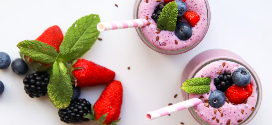 La foto mostra i bicchieri con un frullato sano e frutta a parte, come fragole, mirtilli e more.