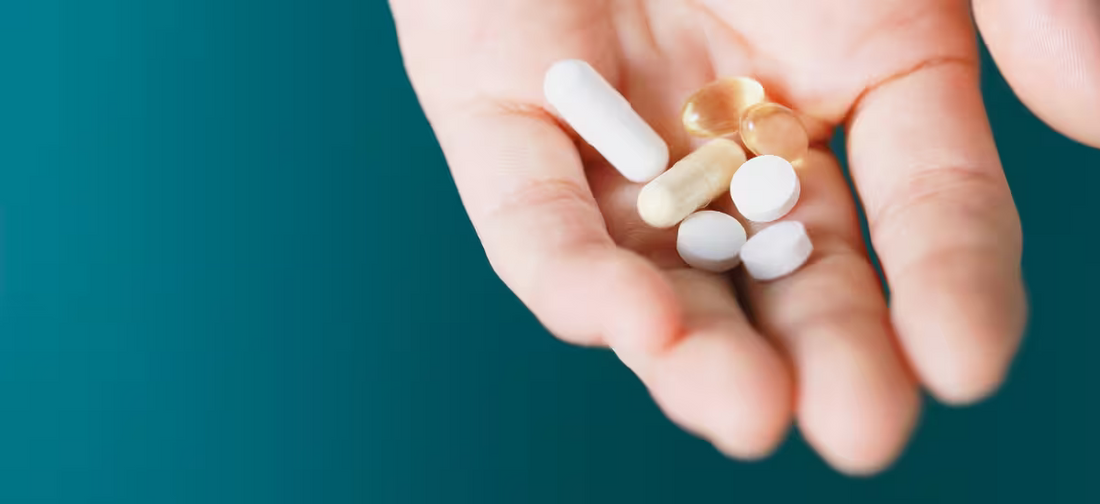 Una mano con una manciata di medicinali su uno sfondo verde