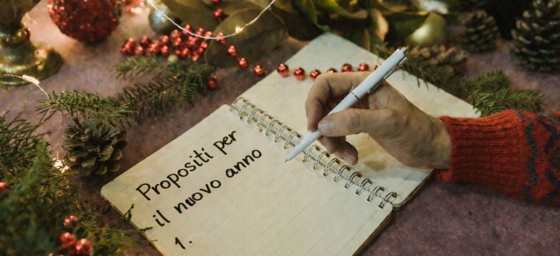 Uomo che scrive i buoni propositi per il nuovo anno in un quaderno