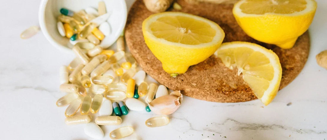 Integratori e vitamine per le difese immunitarie disposti su un piano accanto a un limone tagliato.