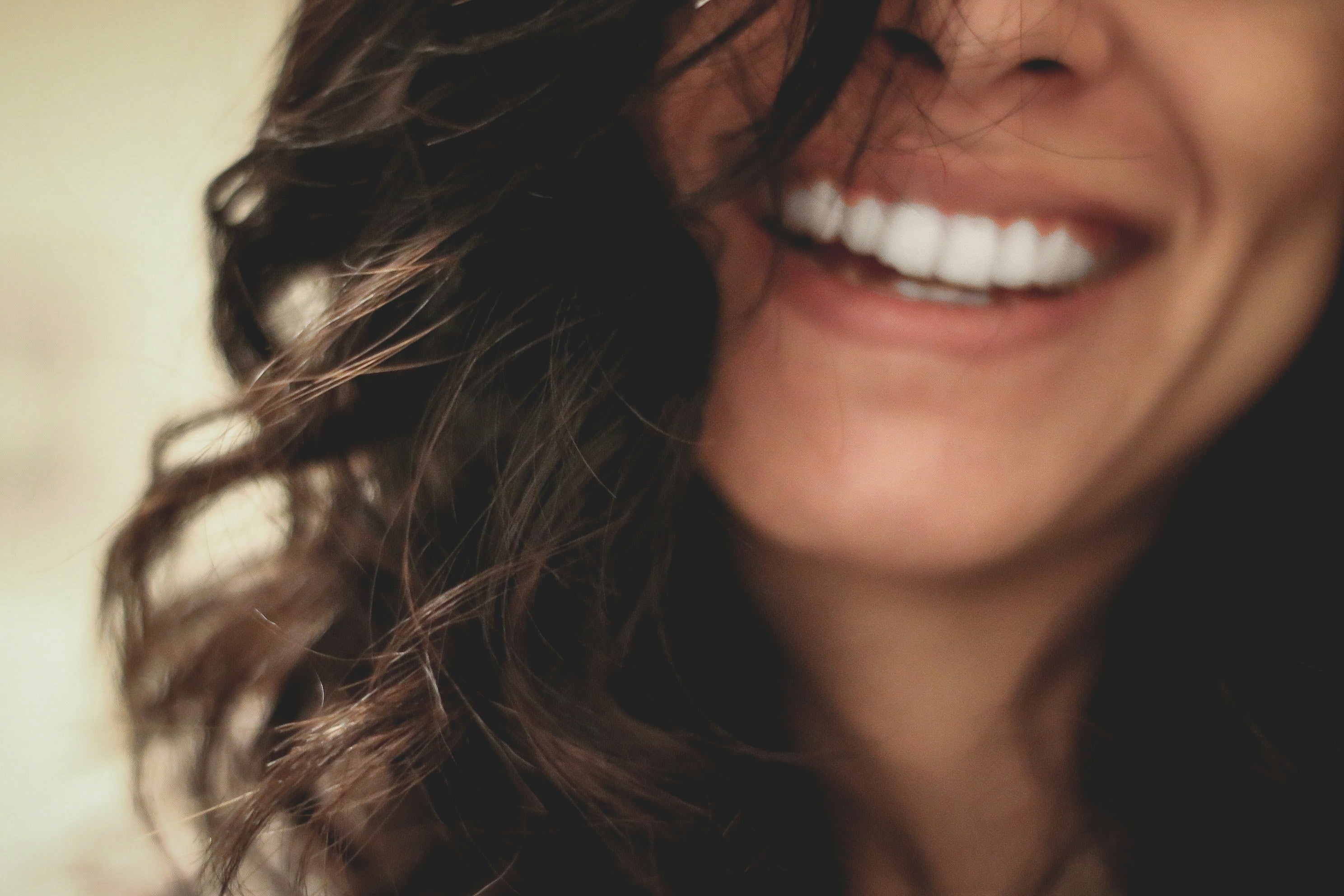 sorriso luminoso di donna con capelli mossi e denti bianchi